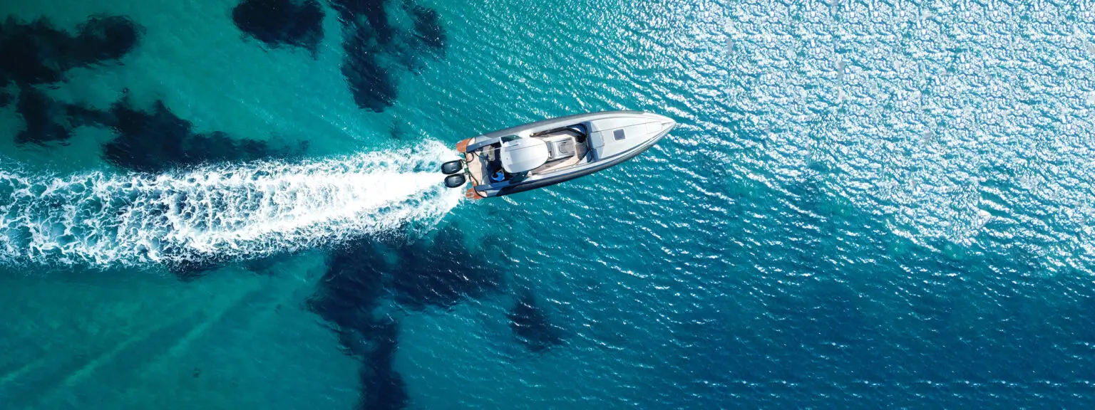 Motorboat cruising on clear blue ocean water, representing professional boat shipping and marine transport services.