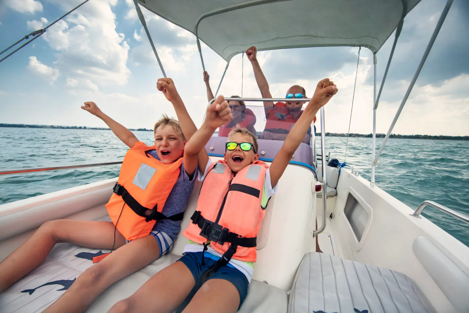 Family enjoying a boat ride on open water, wearing life jackets and celebrating a fun boating experience.