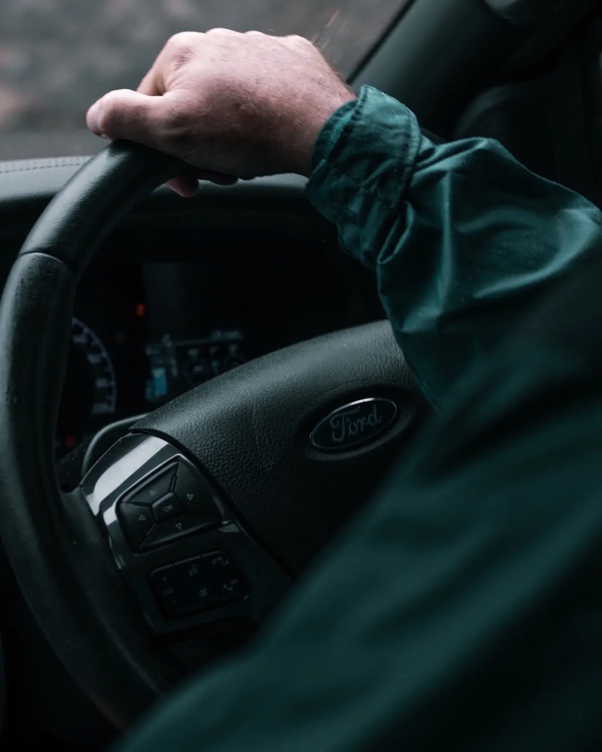 Professional driver holding the steering wheel of a pickup truck, representing safe and reliable transport services.